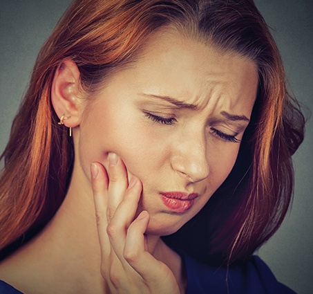 Woman in need of emergency dentistry holding jaw in pain