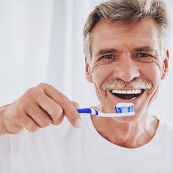 man brushing teeth after dental implant surgery in Flint