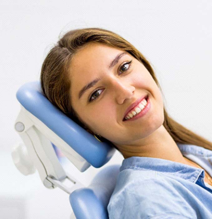 Woman sitting back in dental chair after dental implant salvage in Flint, MI