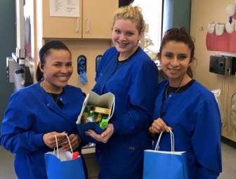 Three dental team members holding gift bags