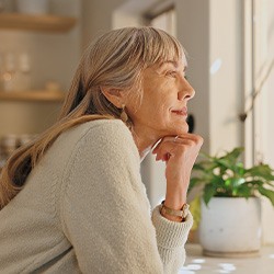 Senior woman smiling while looking out the window at home