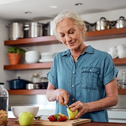 A smiling older woman preparing healthy foods to eat
