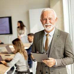 A senior businessman working on a digital tablet in an office