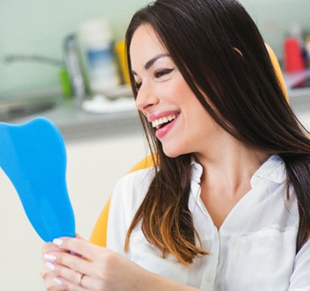 Female dental patient checking smile in mirror