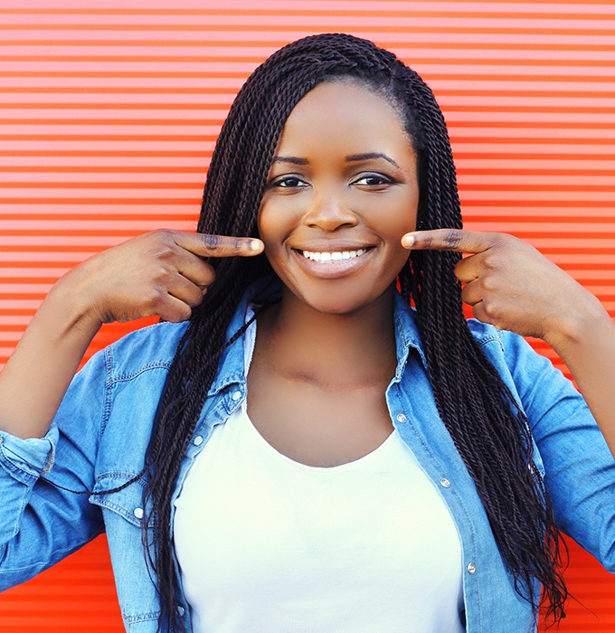 Patient pointing to smile after teeth whitening