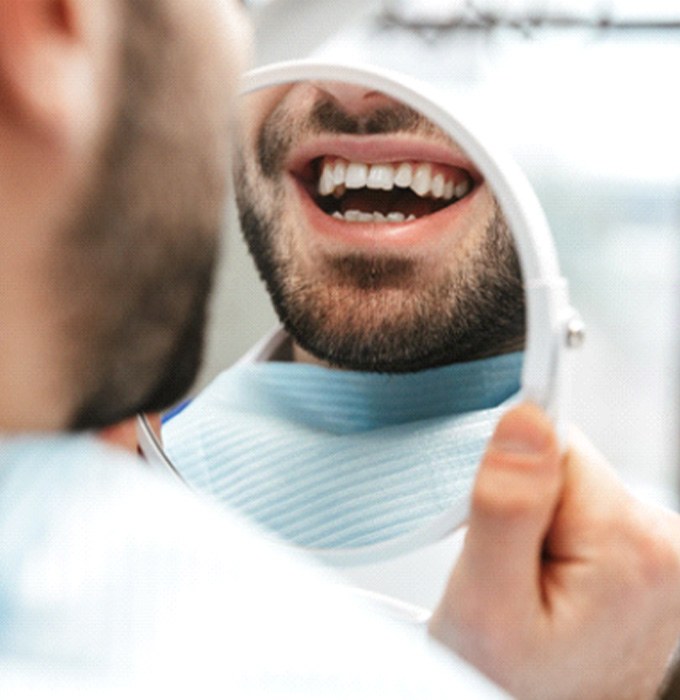 Male dental patient looking at his smile in a mirror