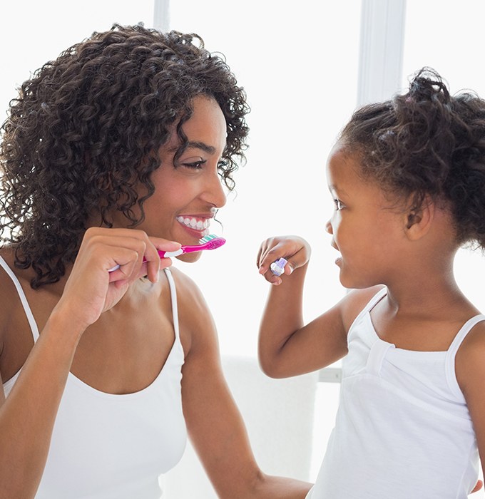 Mother and daughter brushing teeth to prevent dental emergencies