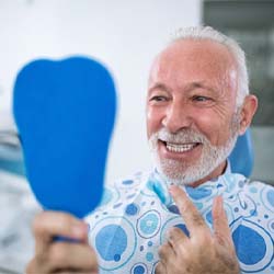 senior man admiring his new smile in a mirror