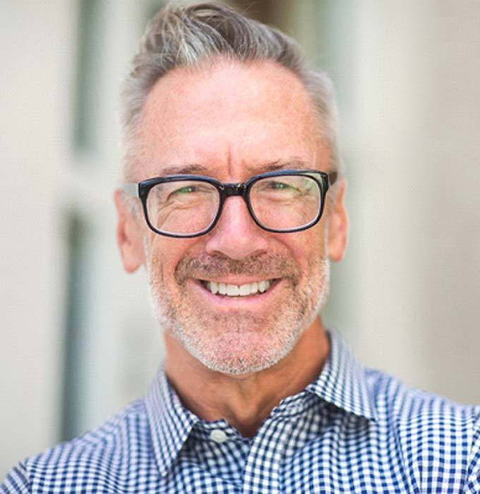 Man with glasses smiling in collared shirt