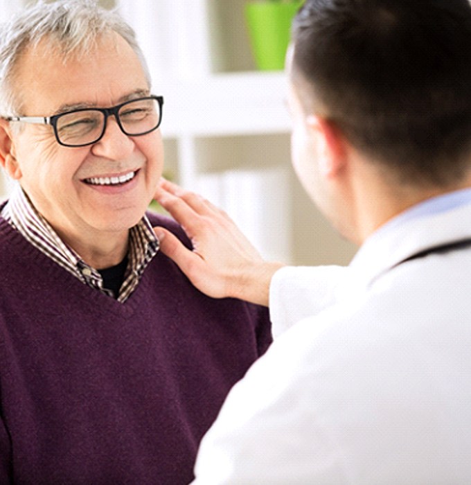 Implant dentist in Flint speaking with an older patient