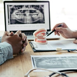 Dentist explaining cost of dental implants in Flint to patient