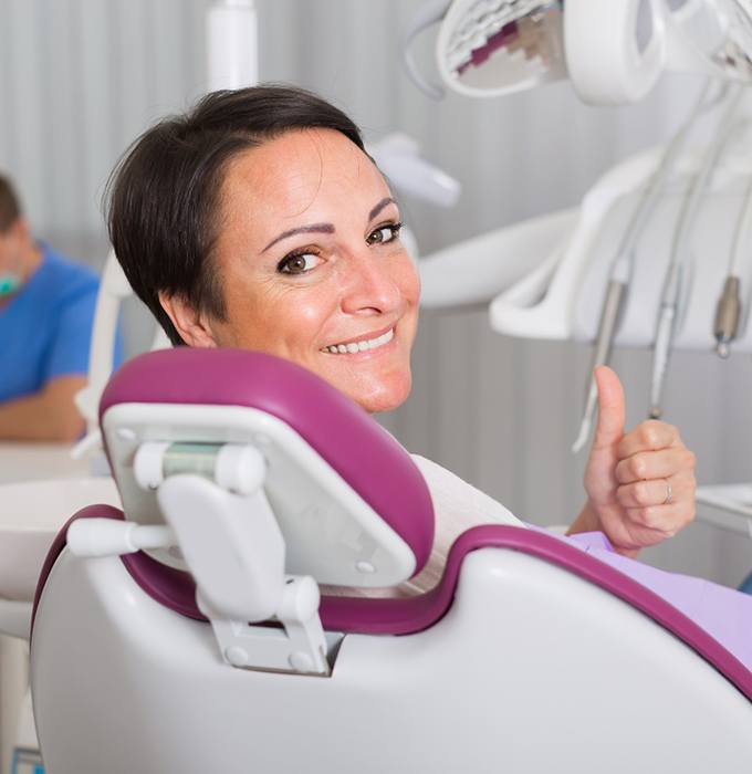 Smiling older woman visiting an implant dentist in Flint