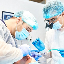 Dentists performing dental implant surgery on male patient