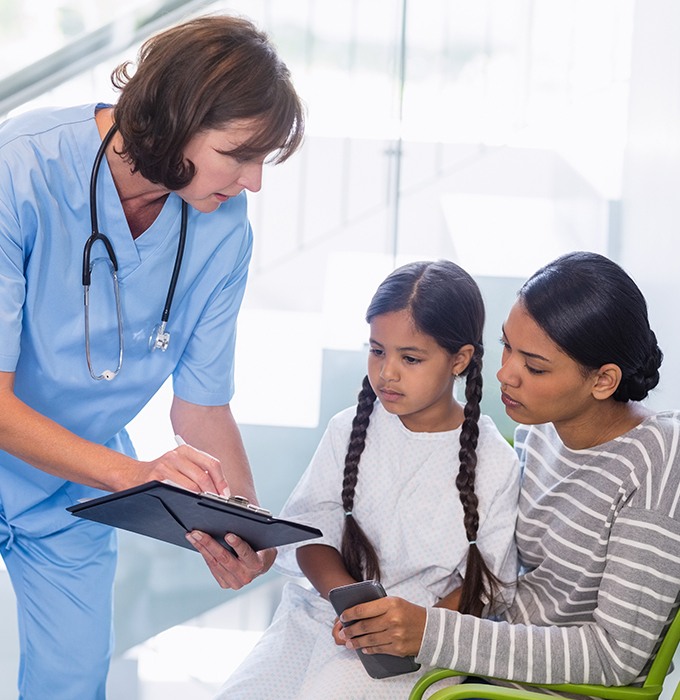 Mother and daughter reviewing dental insurance forms with dental team member