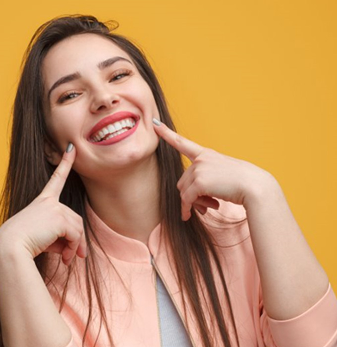 Young woman pointing to her smile