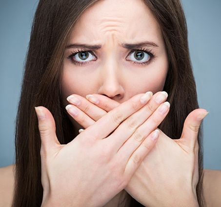 Fearful patient in need of sedation dentistry covering her mouth