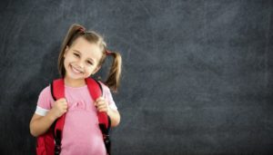 grinning young girl with pigtails wearing a backpack