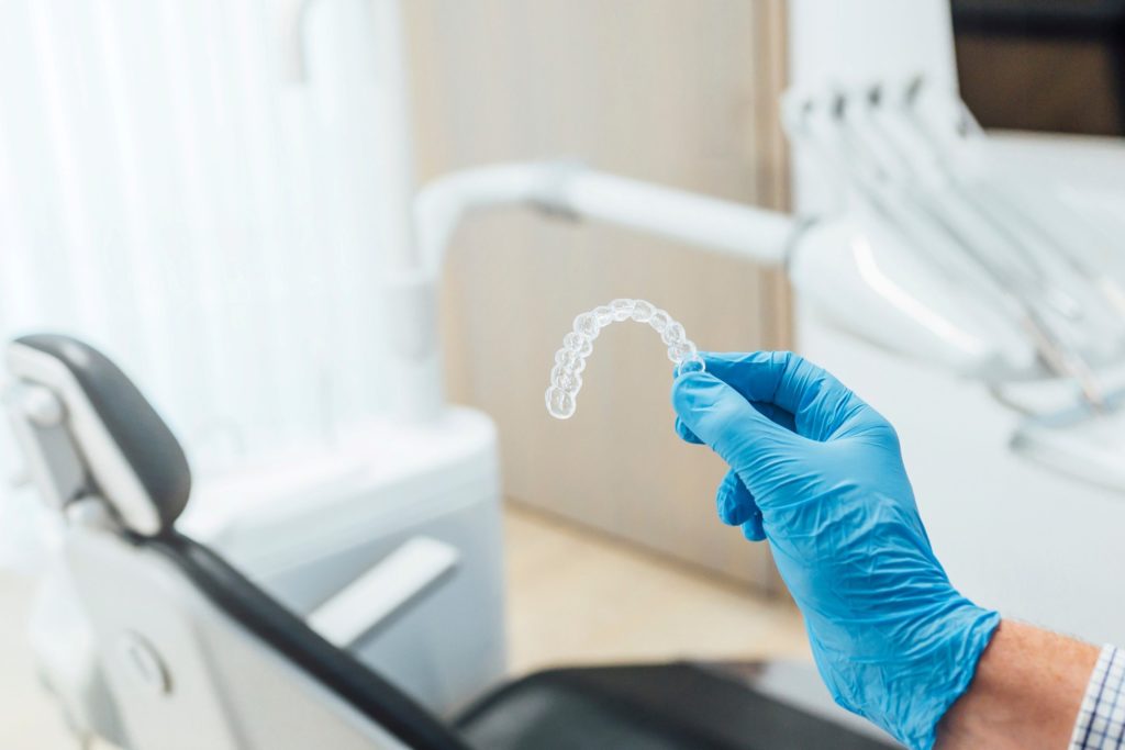 Dentist holding Invisalign aligner with blue glove